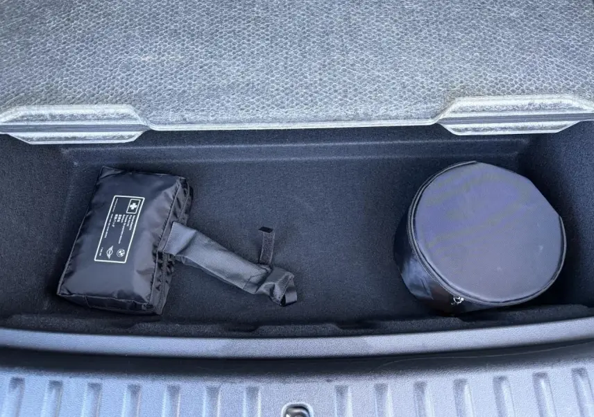 Coffre de BMW X1 noir Saphir 2025 vu de dessus, avec trousse de secours et rangement rond noir.