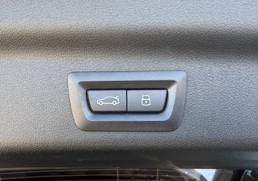 Boutons de commande du hayon et de verrouillage intégrés dans le panneau intérieur noir du coffre d'un BMW X1 noir Saphir.