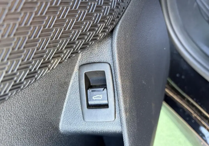 Détail du bouton d'ouverture du coffre sur la portière intérieure d'une BMW X1 noir saphir.