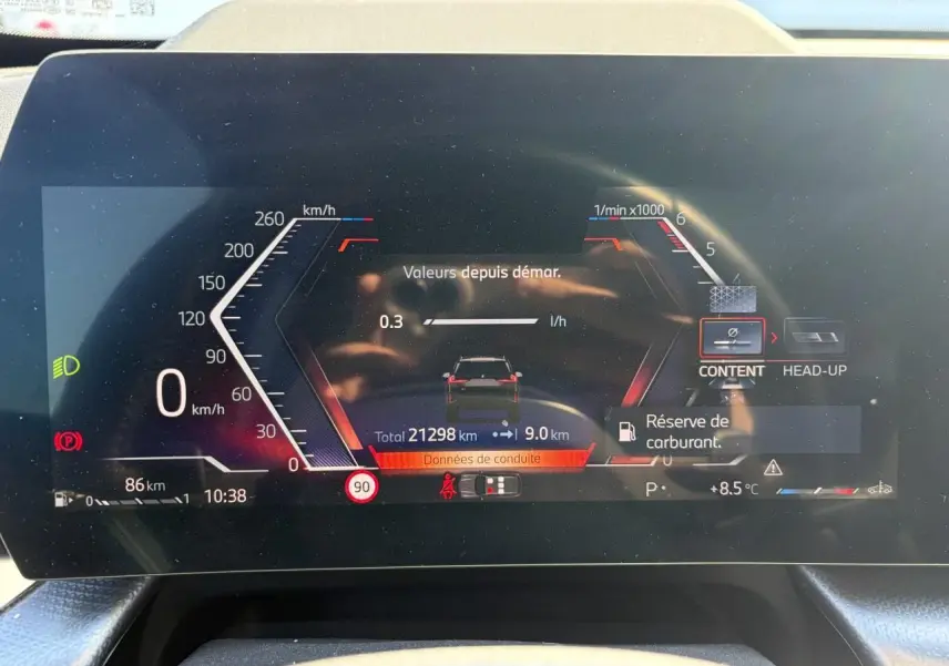Affichage numérique du tableau de bord BMW X1 2025, montrant la consommation, vitesse 0 km/h et alerte réserve carburant.