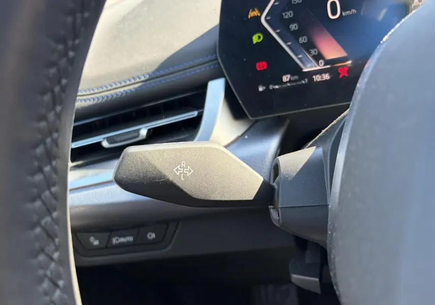 Gros plan sur le commodo gauche noir mat et le combiné d'instruments digital du BMW X1 noir Saphir, vue depuis le siège conducteur.