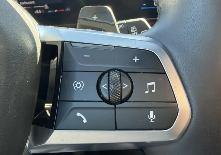 Gros plan sur les commandes multifonctions du volant cuir noir du BMW X1 2025, avec boutons de volume et appels.