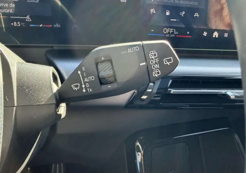 Gros plan sur la commande d’essuie-glace à gauche du volant dans l’habitacle noir du BMW X1 2025.