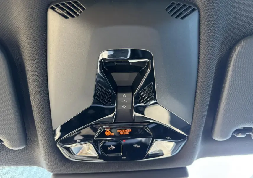 Vue en contre-plongée du plafonnier noir brillant avec commandes et indicateur airbag du BMW X1 noir Saphir 2025.