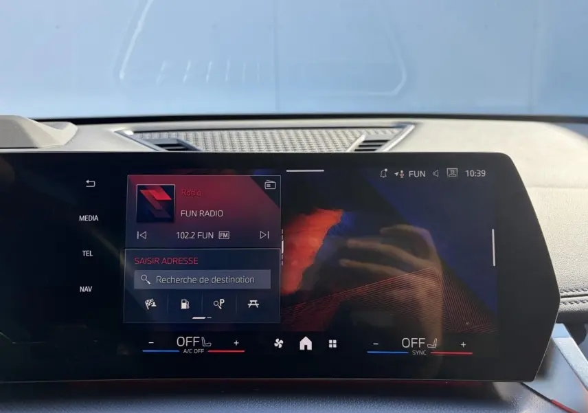 Écran tactile incurvé du tableau de bord de la BMW X1 noir Saphir, affichant la radio et la navigation.