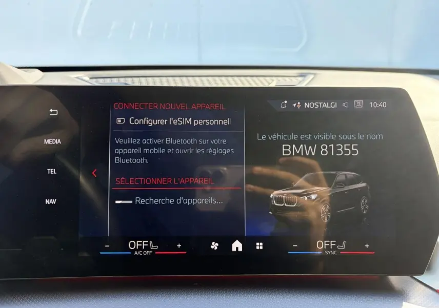 Écran tactile intérieur montrant une image 3/4 avant d’un BMW X1 noir Saphir avec interface connectivité Bluetooth.