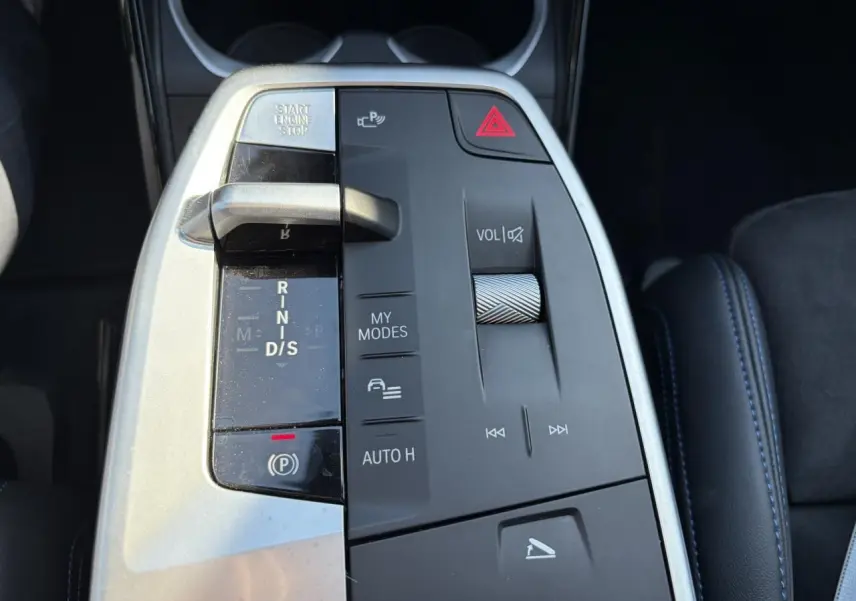 Gros plan sur la console centrale du BMW X1 noir Saphir, avec levier de vitesse et commandes multimédia visibles.