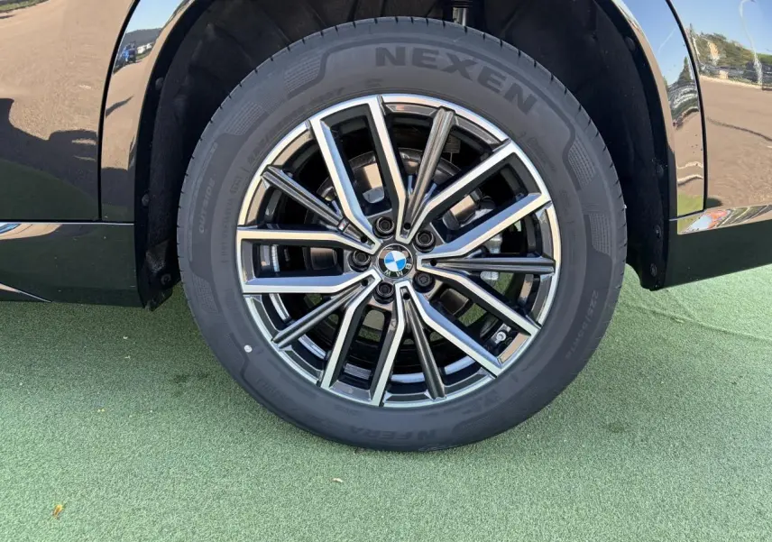 Gros plan sur la roue avant droite du BMW X1 noir saphir, mettant en valeur la jante alliage 18 pouces style 838 M bicolore.