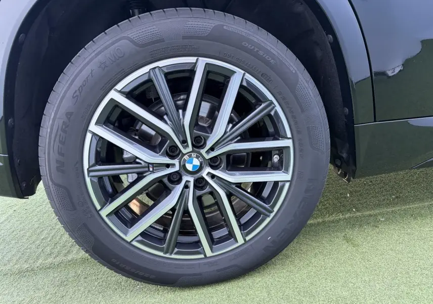 Gros plan sur la roue avant droite du BMW X1 noir saphir, mettant en valeur la jante alliage 18 pouces style 838 M bicolore.