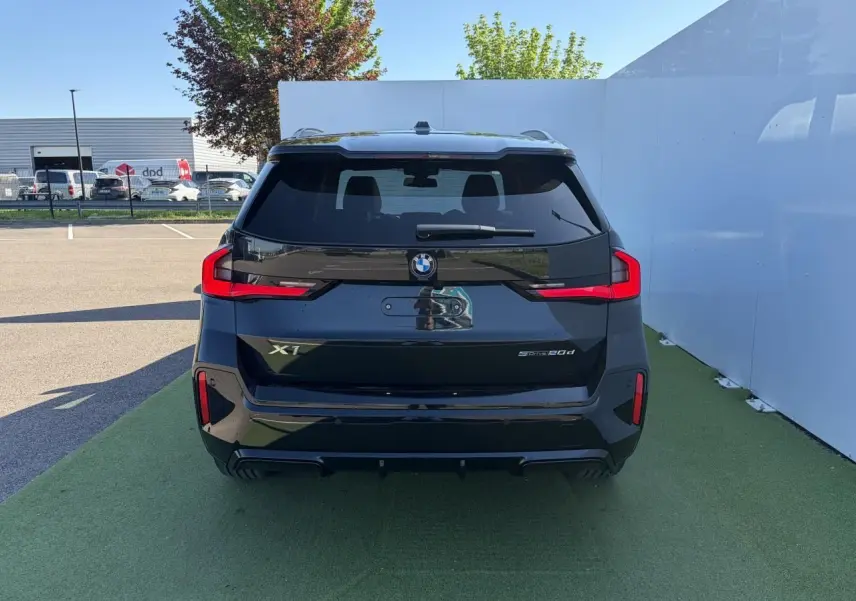 Vue arrière d’une BMW X1 noire Saphir 2025 avec feux LED distinctifs et toit ouvrant panoramique visible.