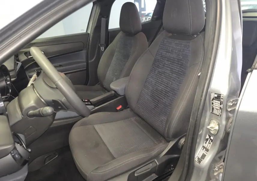 Vue intérieure côté conducteur de l'Alfa Romeo Junior 1.2 Ibrida gris, montrant les sièges avant et le volant multifonctions.