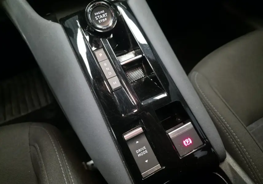 Vue rapprochée de la console centrale noire brillante avec sélecteur de mode de conduite et frein de parking électrique de l'Alfa Romeo Junior 1.2 Ibrida.