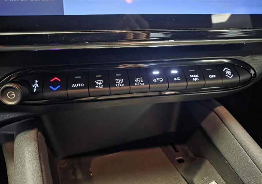 Gros plan sur la console centrale de l'Alfa Romeo Junior 1.2 Ibrida gris, montrant les commandes de climatisation et volume.