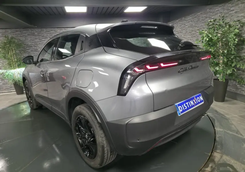 Vue 3/4 arrière gauche de l'Alfa Romeo Junior gris métallisé avec feux arrière LED et jantes noires brillantes.