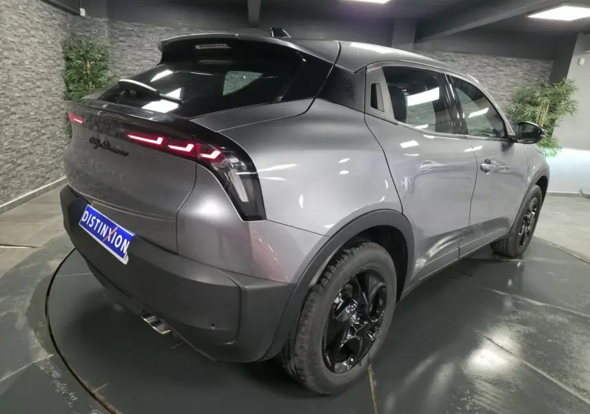 Vue 3/4 arrière droite de l'Alfa Romeo Junior gris métallisé avec feux arrière LED et jantes alliage noires.