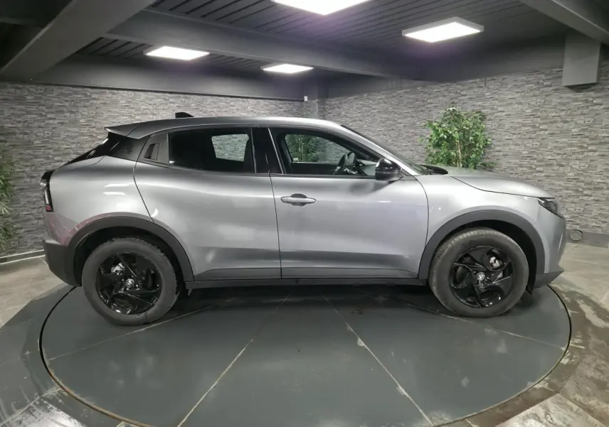 Vue de profil côté gauche d'une Alfa Romeo Junior 1.2 Ibrida gris métallisé avec jantes noires et toit noir.