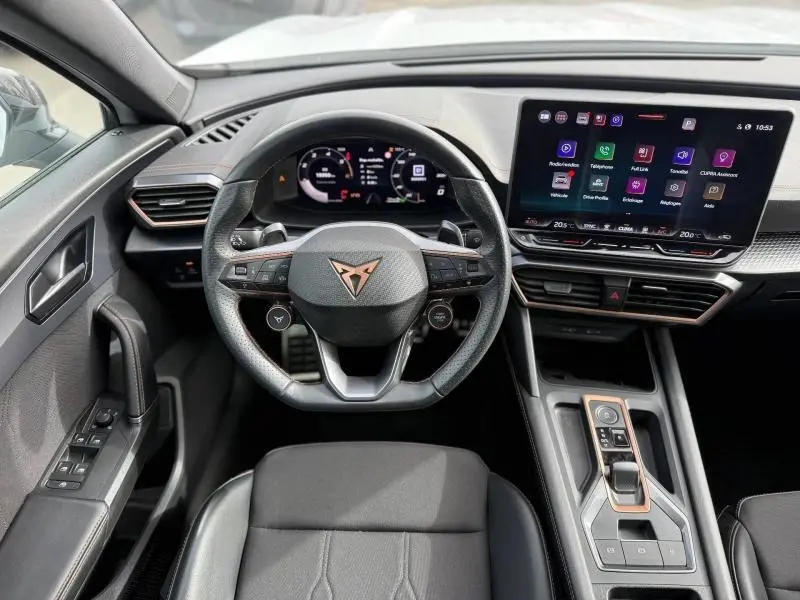 Vue intérieure centrée sur le volant multifonction et l'écran tactile du tableau de bord du CUPRA Formentor blanc Nevada 2025.