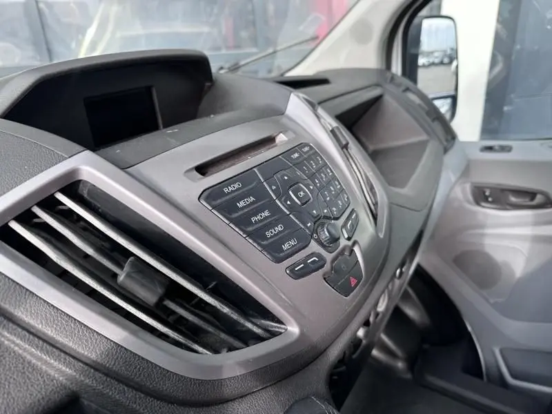 Tableau de bord et console centrale du Ford Transit Fourgon blanc, vue intérieure côté passager avec commandes audio visibles.