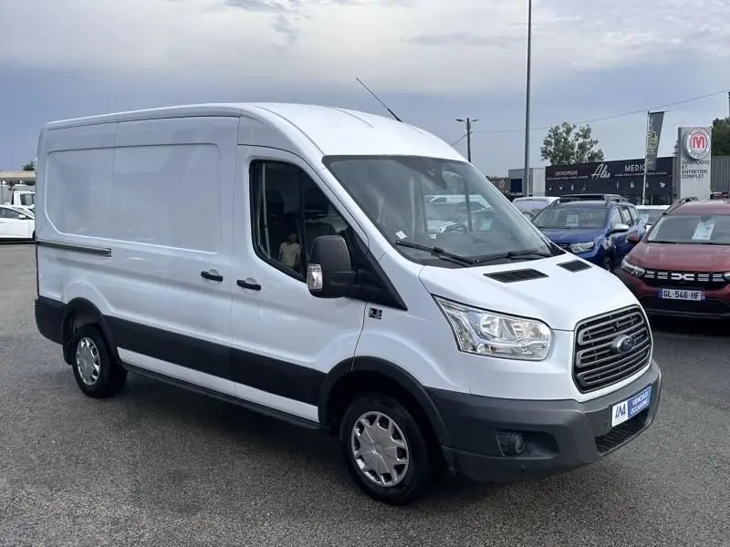 Fourgon Ford Transit blanc en 3/4 avant droit, avec calandre noire et protections latérales noires visibles.