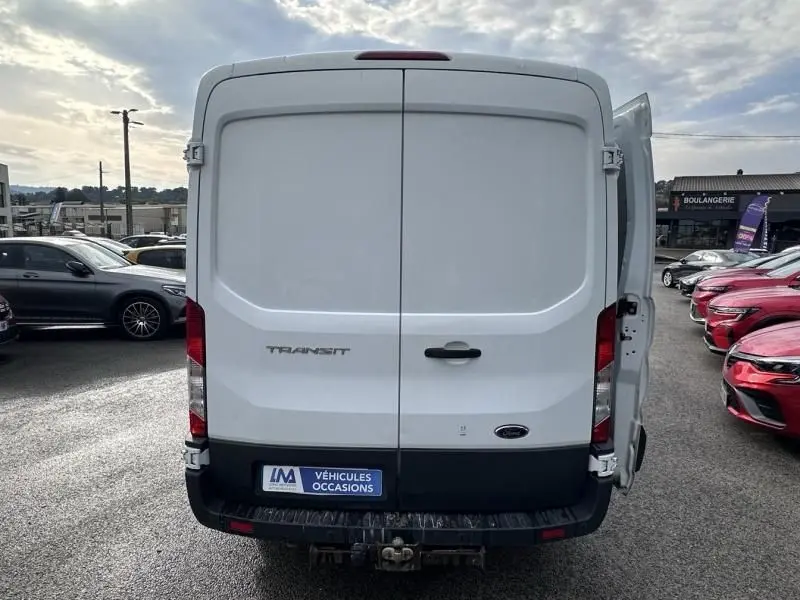 Vue arrière d’un Ford Transit Fourgon blanc 2019 avec porte droite partiellement ouverte et attelage visible.