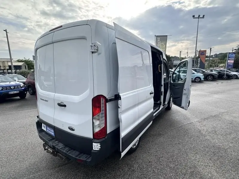 Vue 3/4 arrière droite d’un Ford Transit Fourgon blanc 2019 avec porte latérale et porte conducteur ouvertes.