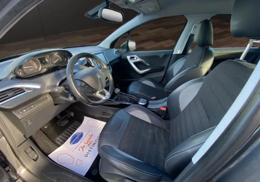 Vue intérieure côté conducteur du Peugeot 2008 gris foncé, montrant les sièges en cuir et le tableau de bord moderne.