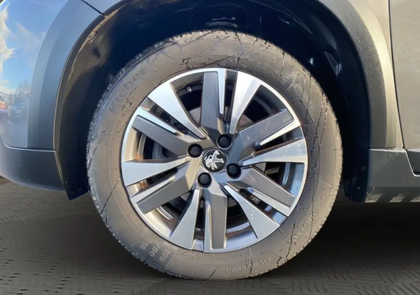 Gros plan sur la roue avant droite avec jante alliage gris et partie de la carrosserie gris foncé du Peugeot 2008.