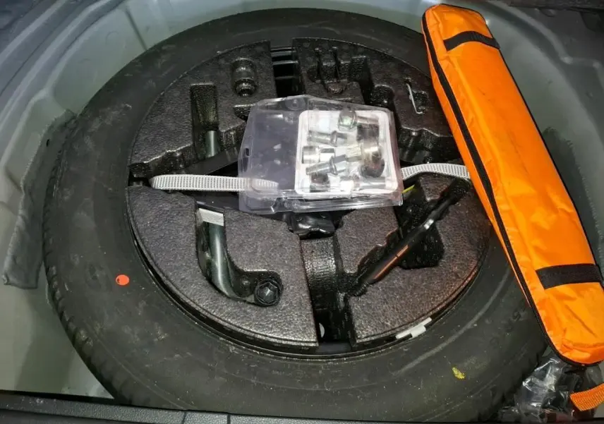 Vue rapprochée de la roue de secours et des outils de bord dans le coffre du SEAT Arona gris foncé 2021.