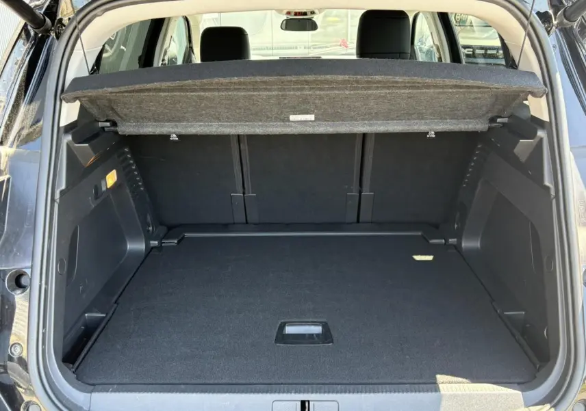 Coffre ouvert vu de l'arrière d'un Citroën C5 Aircross Hybrid noir Perla avec hayon électrique et cache-bagages relevé.