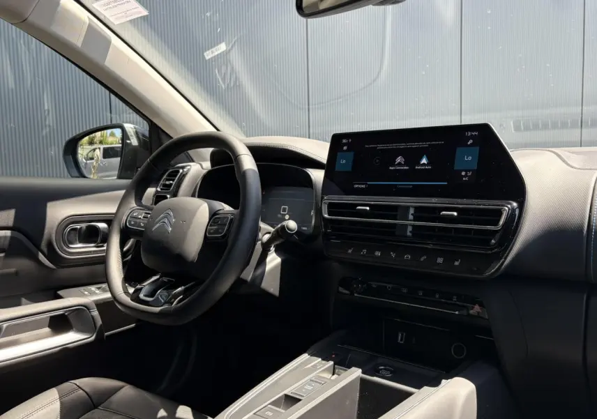 Intérieur noir de la Citroën C5 Aircross Hybrid 2025, vue côté conducteur sur volant et écran tactile central.