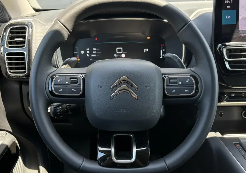 Vue frontale du volant noir du Citroën C5 Aircross Hybrid 2025 avec commandes intégrées et tableau de bord numérique.