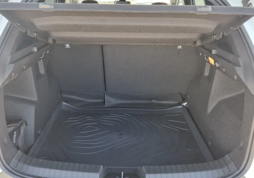 Vue intérieure du coffre ouvert du Dacia Duster blanc 2026, montrant un tapis de protection noir et un éclairage latéral.