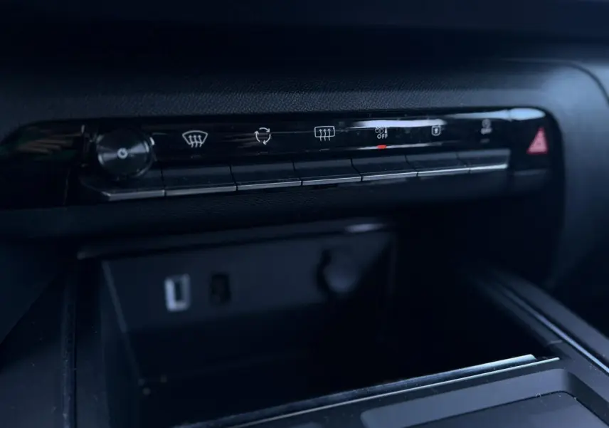 Détail de la console centrale noire du Citroën C5 Aircross Hybrid 2025 avec commandes climatisation et prises USB visibles.