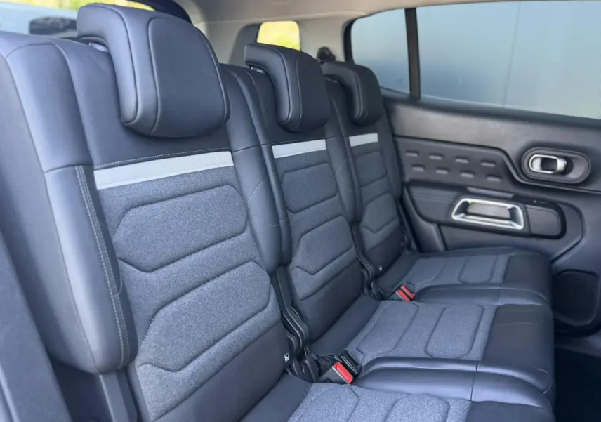 Vue latérale droite des trois sièges arrière indépendants gris foncé du Citroën C5 Aircross Hybrid 2025 avec appuis-tête réglables.