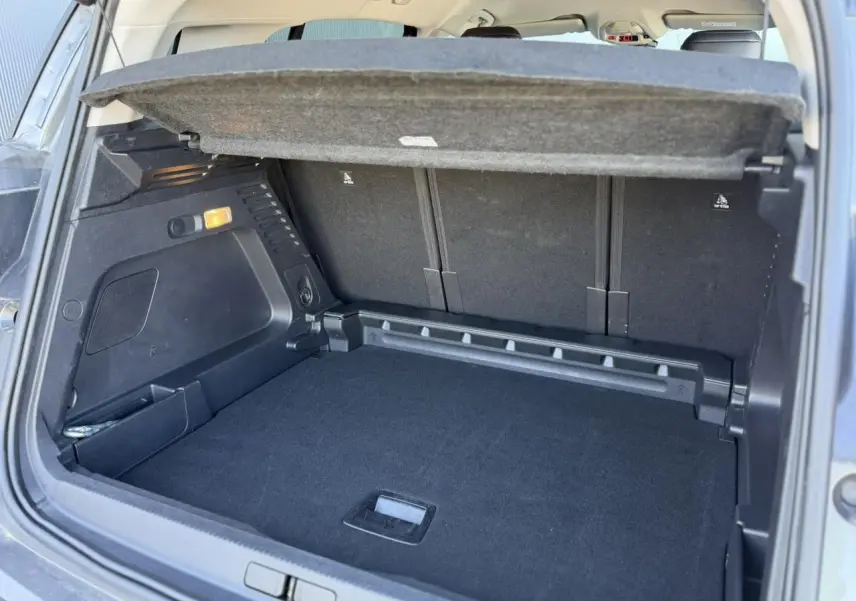 Vue intérieure du coffre ouvert du Citroën C5 Aircross Hybrid gris Platinium, montrant le plancher modulable et la tablette arrière.