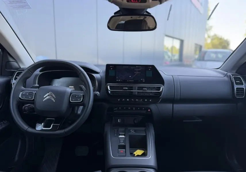Vue intérieure avant du Citroën C5 Aircross Hybrid gris Platinium, volant multifonction et écran tactile central.