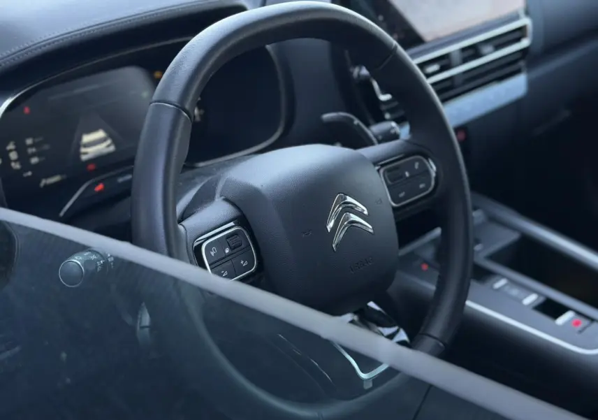 Vue rapprochée du volant cuir noir et du tableau de bord numérique du Citroën C5 Aircross Hybrid 2025.