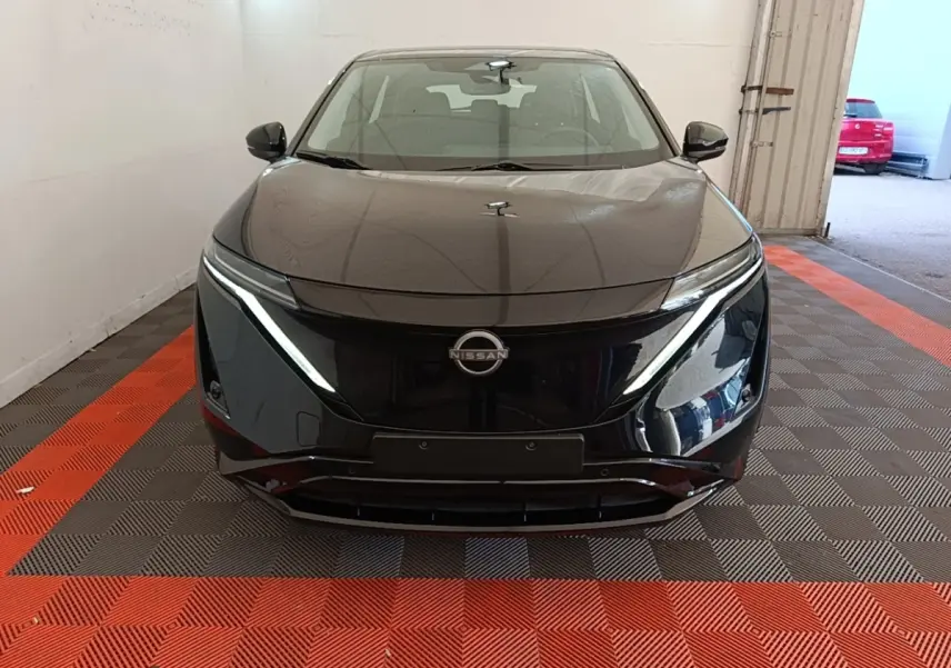 Vue de face d'une Nissan Ariya noire 63kWh 218ch Engage, avec phares LED et calandre lisse électrique.