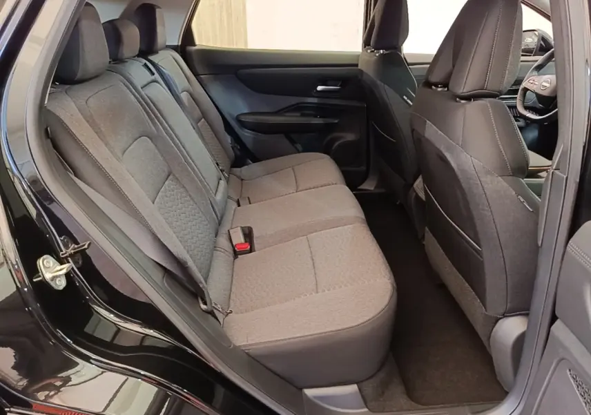 Vue intérieure côté gauche sur la banquette arrière grise du Nissan Ariya noir 2026 avec sièges tissu et ceintures visibles.