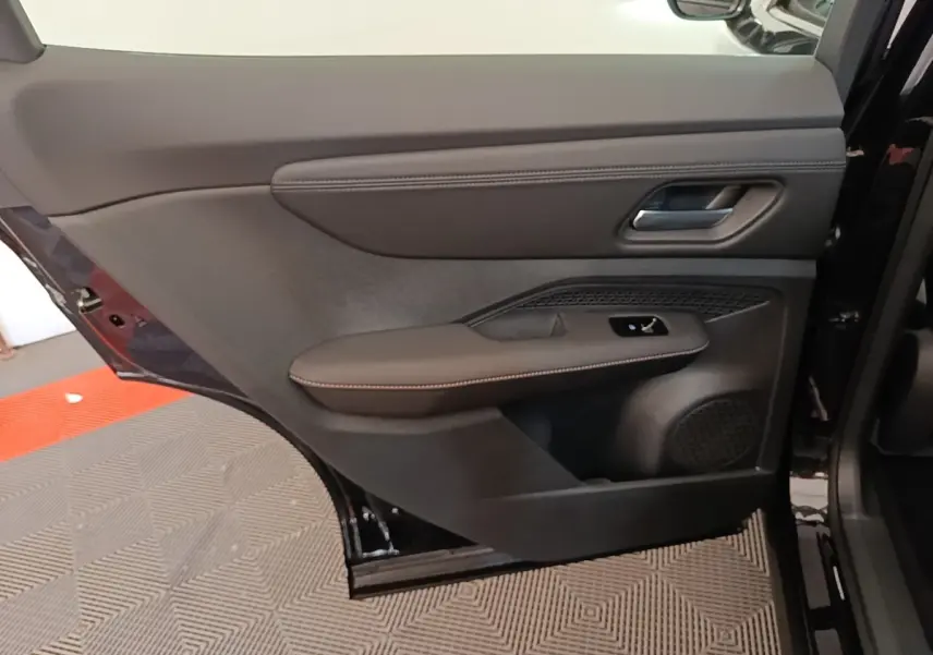 Vue intérieure du panneau de porte arrière droite noir du Nissan Ariya 63kWh 218ch Engage avec accoudoir cuir et commande de vitre.