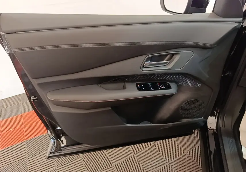 Porte avant gauche ouverte du Nissan Ariya noir, montrant les commandes électriques et le revêtement intérieur en cuir.