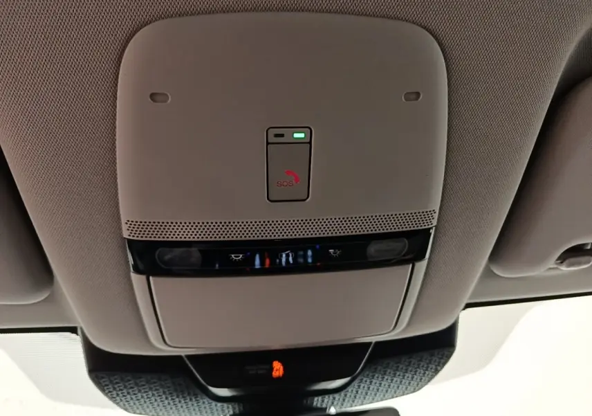 Vue intérieure du plafonnier beige du Nissan Ariya noir 2026 avec bouton SOS et éclairages intégrés.