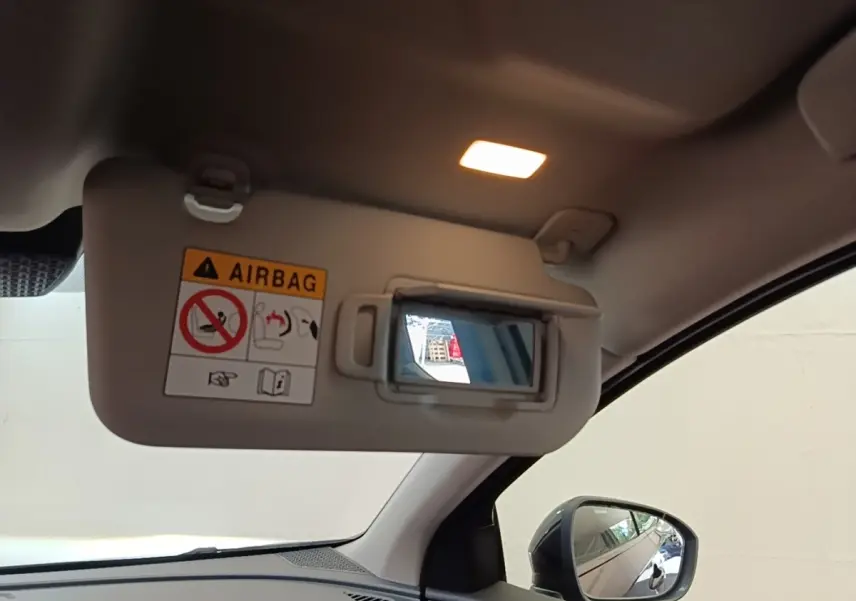 Détail intérieur du pare-soleil côté conducteur avec miroir éclairé et rétroviseur extérieur noir visible sur Nissan Ariya noir.