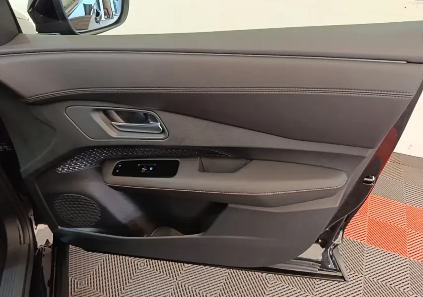 Vue côté gauche de la porte avant noire du Nissan Ariya 63kWh 218ch Engage avec garniture cuir et commandes électriques.