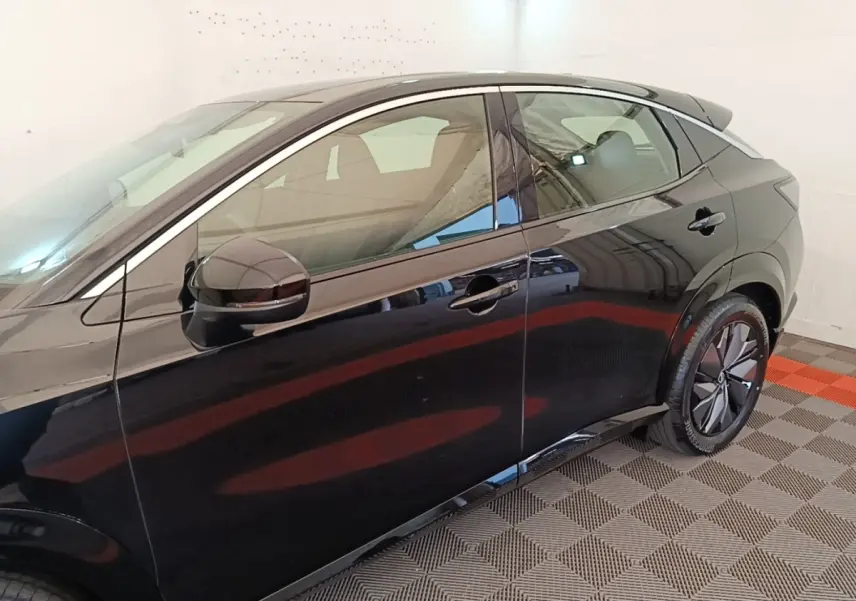 Vue latérale côté gauche du Nissan Ariya noir 63kWh 218ch Engage avec jantes modernes et rétroviseur électrique.