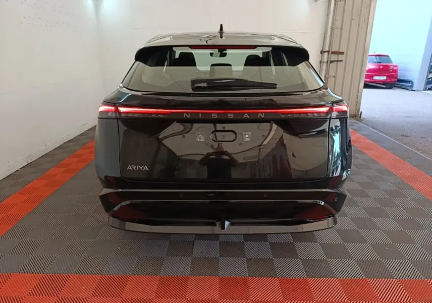 Vue arrière d'un Nissan Ariya noir avec feux arrière LED continus et logo Nissan lumineux.