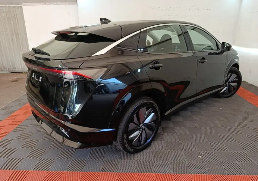 Nissan Ariya 63kWh noir, vue 3/4 arrière droit, feux arrière LED et jantes aérodynamiques visibles.