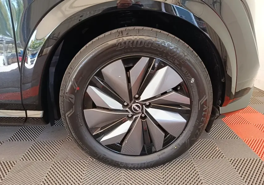 Gros plan sur la roue avant droite noire du Nissan Ariya 63kWh 218ch Engage avec jante design bicolore.