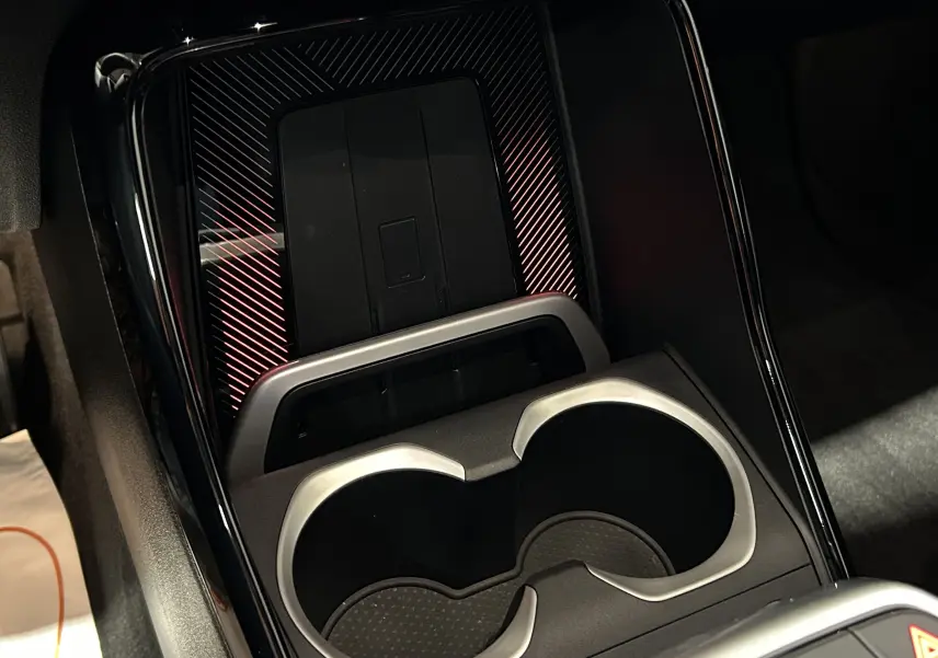 Gros plan sur la console centrale du BMW X1 2024 M Sport, montrant les porte-gobelets et la zone de recharge sans fil.