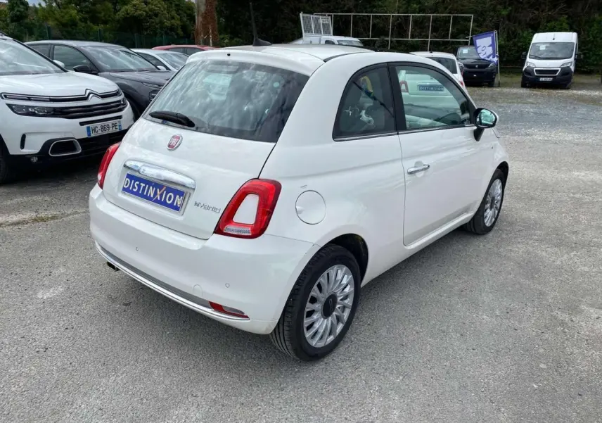 Vue 3/4 arrière droite d'une FIAT 500 blanche 2024 avec jantes alliage 16'' Spider et toit panoramique fixe.